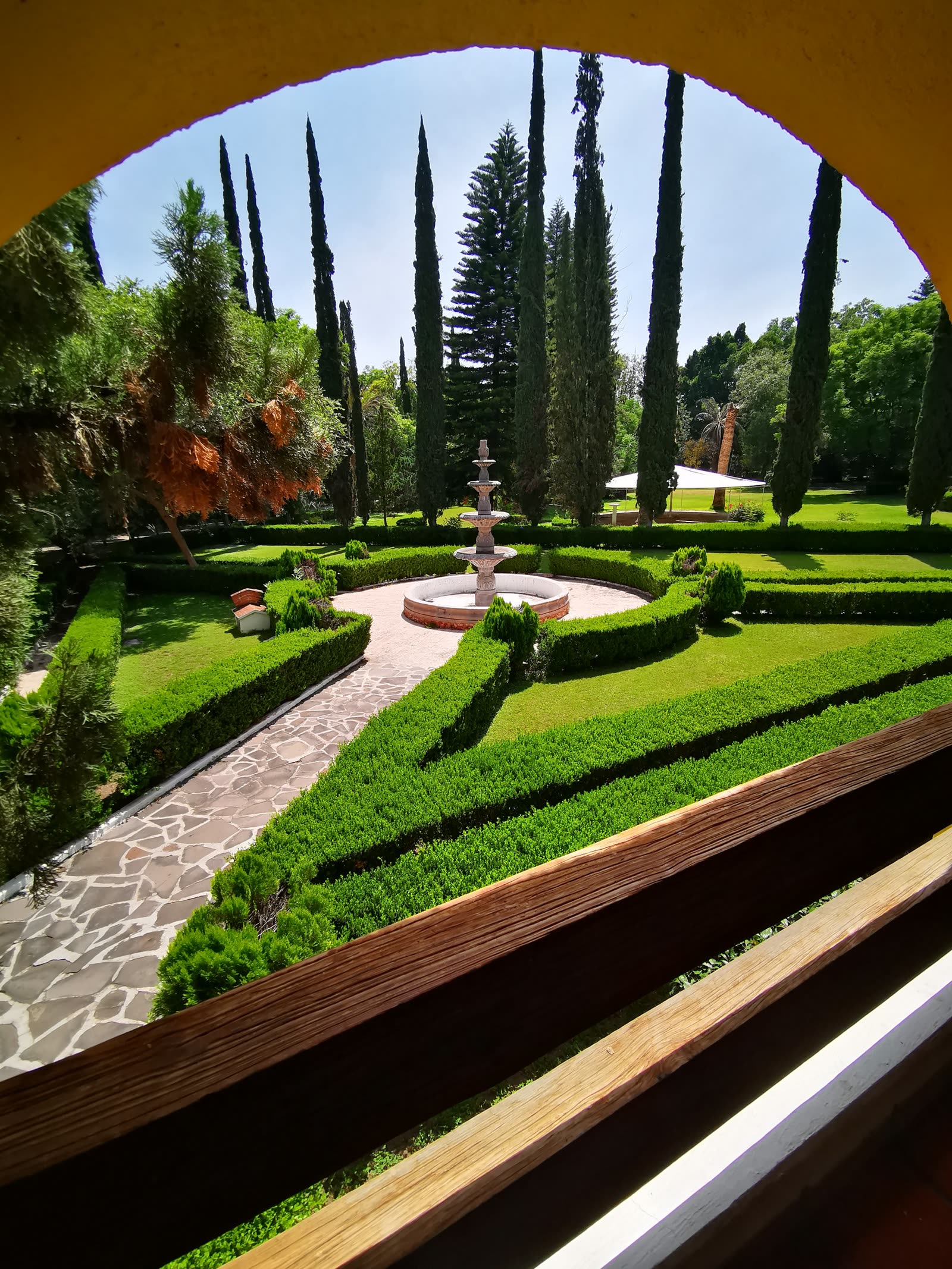Jardín con la fuente y los cipreses visto desde un arco